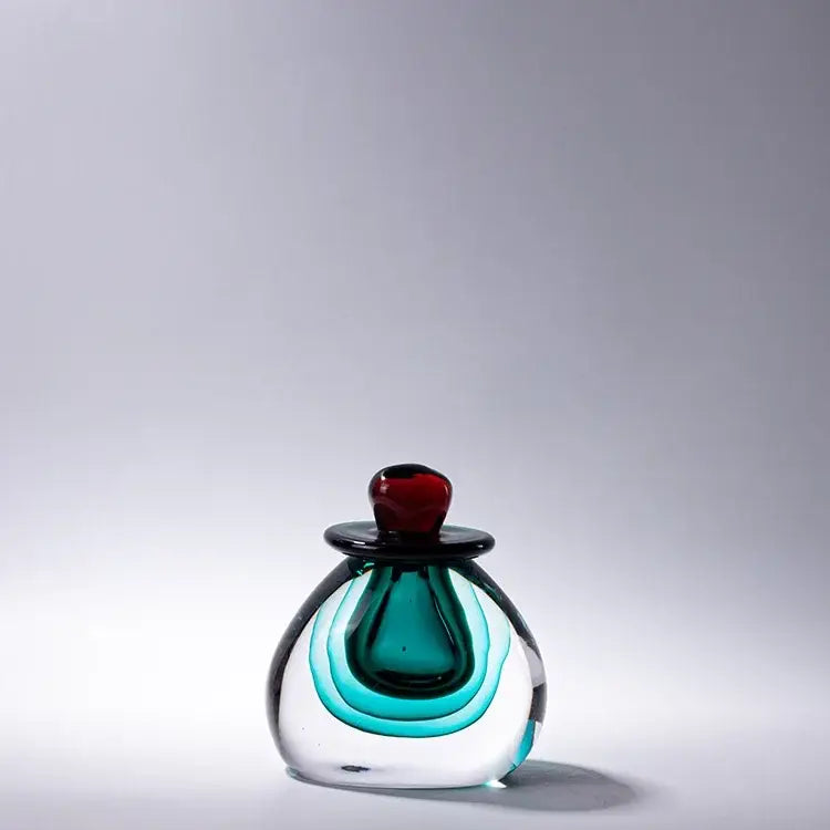 Modern double stained glass vase featuring teal and green swirls with a black rimmed stopper and red cap for living room decor