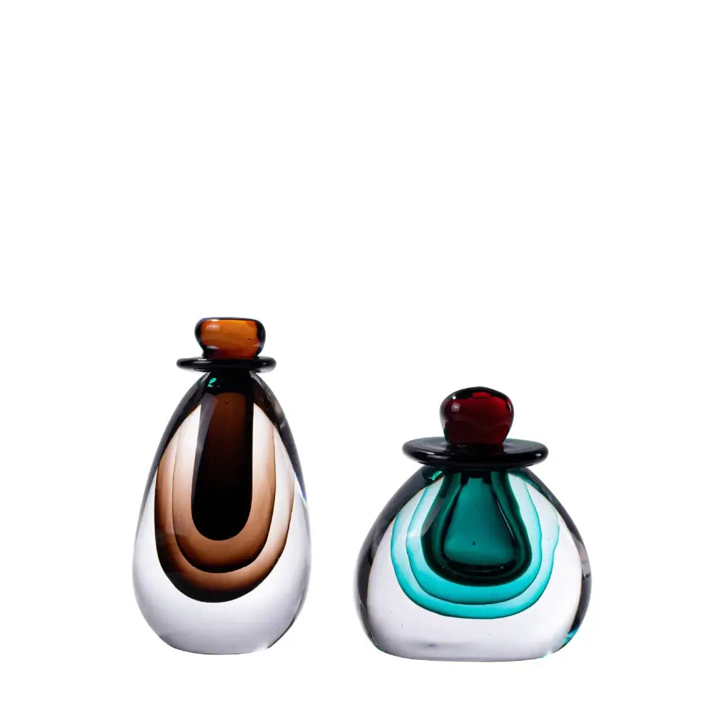 Two hand-blown double stained glass perfume bottles with amber and clear layered swirls and rounded stoppers