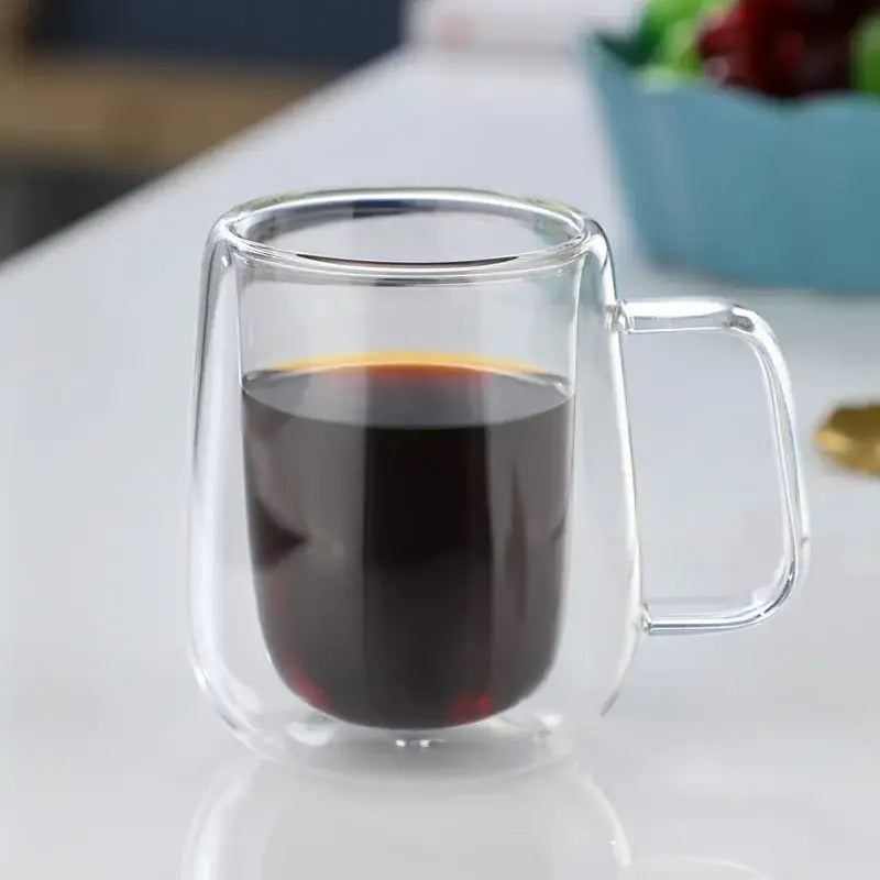 Modern double wall glass coffee cup filled with dark coffee featuring a clear handle for espresso use