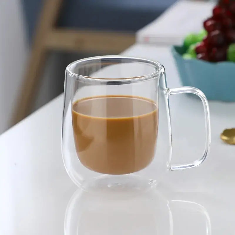 Clear double wall glass coffee cup with handle filled with brown liquid from modern espresso mug set