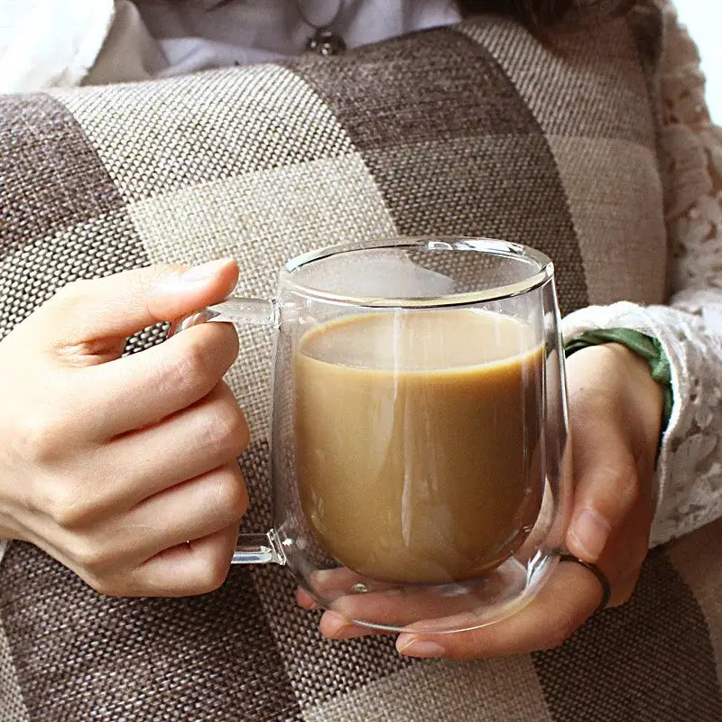 Clear double wall glass coffee cup with handle filled with coffee in modern double wall kitchen espresso mug set