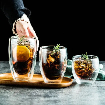 Set of three clear modern double wall glass coffee mugs with ice lemon slices and rosemary for kitchen use