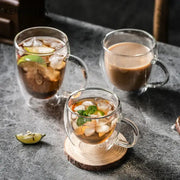 Modern double walled transparent glass cups filled with iced beverages garnished with lime and mint leaves