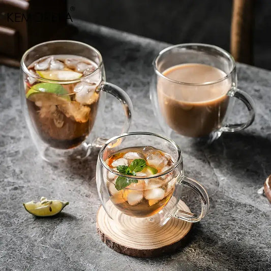 Modern double walled transparent glass cups filled with iced beverages garnished with lime and mint leaves