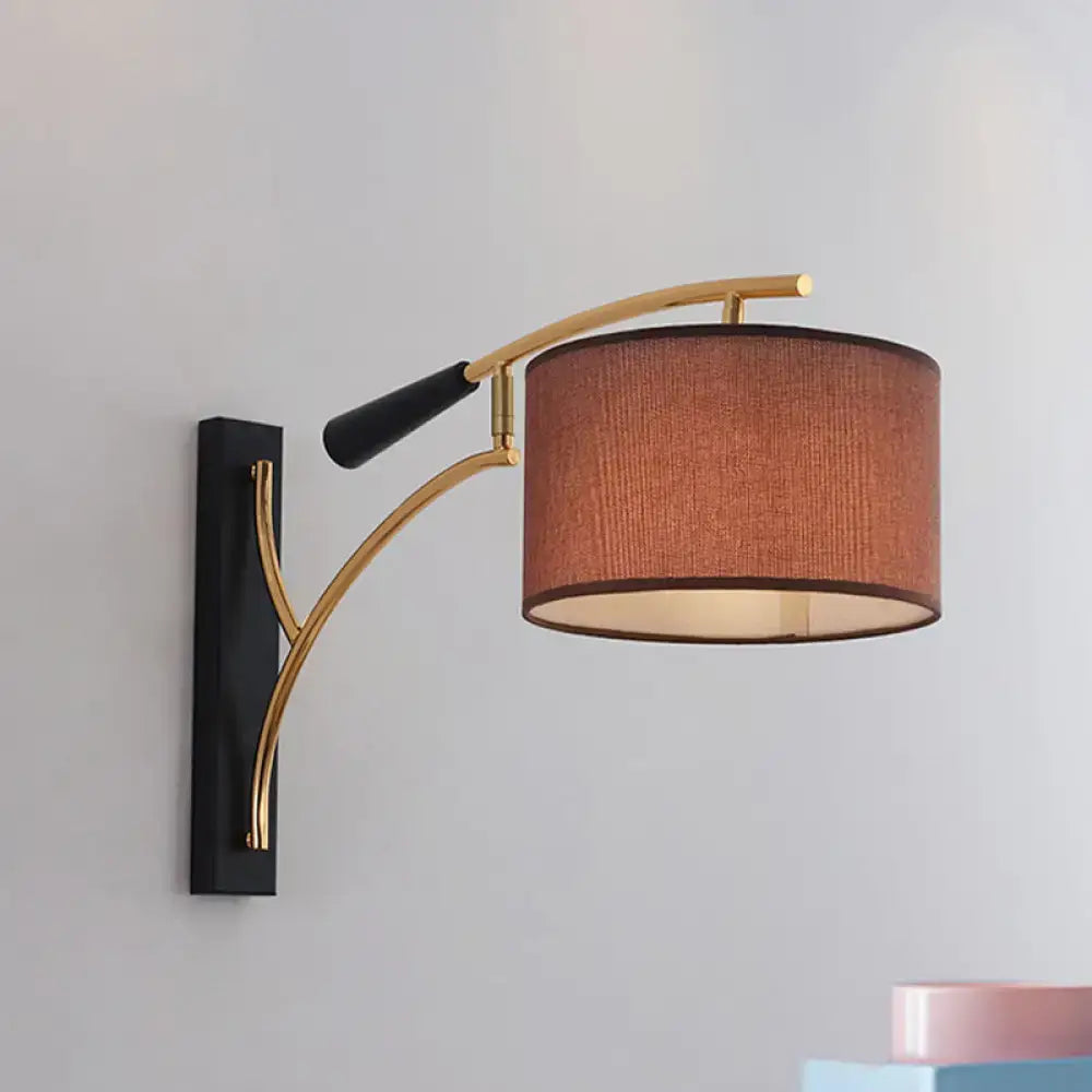 Modern drum shade wall lamp with a curved gold-toned arm and flaxen coffee terracotta fabric shade for bedroom use