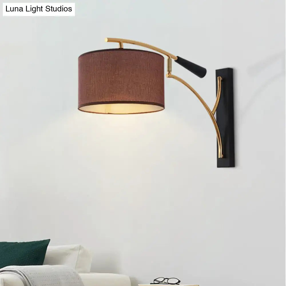 Modern drum shade wall lamp in flaxen coffee with a warm brown fabric shade and gold metal arms for bedroom use