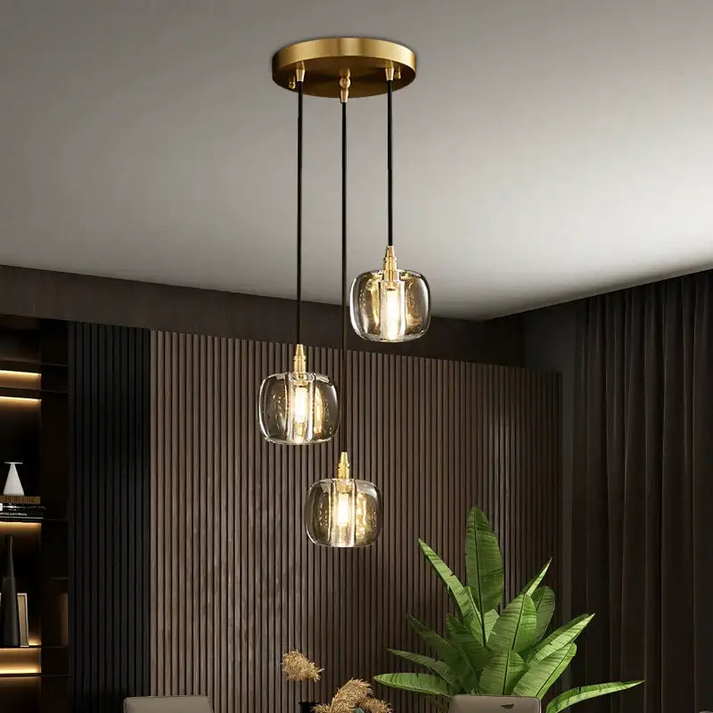 Modern brass-finished pendant light with three clear glass globes and black cords for elegant rotating staircase decorbites decor