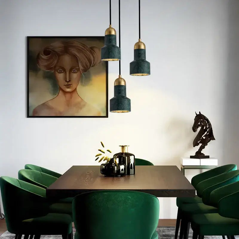 Three modern emerald green and brass led pendant lamps with textured shades hang above a dining table