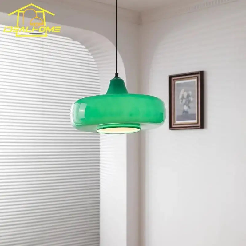 A sleek translucent emerald green glass pendant light with a rounded design hanging from a black cord