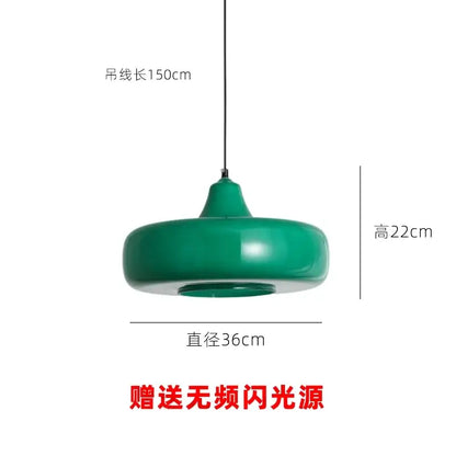 Modern emerald green glass pendant light with a sleek rounded disc shape and smooth curved edges for dining rooms