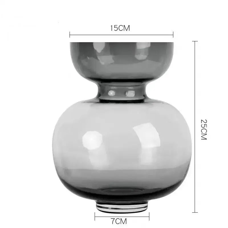 A sleek two-tiered dark gray glass vase with smooth contours in a modern green gourd vase terrarium set