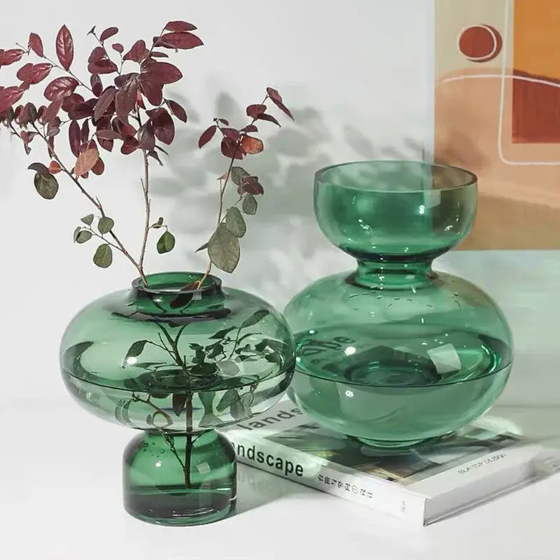 Two translucent emerald green glass gourd vases with bulbous shapes and wide openings for modern living rooms