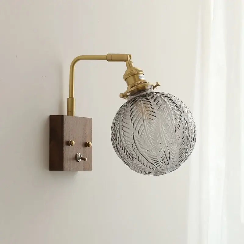 Vintage-style bedroom sconce wall lights with glass copper led ornate etched leaf glass shade and brass fixture on dark wood base