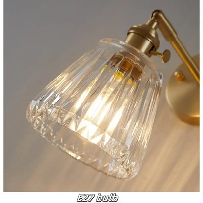 Modern faceted clear glass copper wall lights with a brass-finished metal arm and base for bedroom sconce use