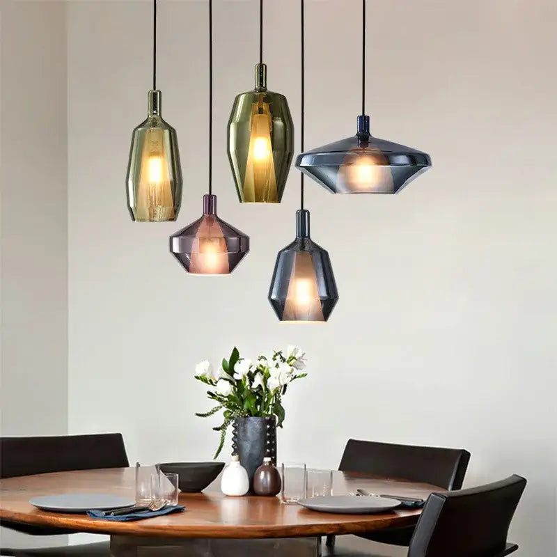 Five modern faceted glass pendant lights in amber green and dark blue hues enhance dining room home art decor