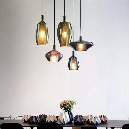 Five modern faceted glass pendant lights in gold bronze and dark gray hang above a dining table for home art decor