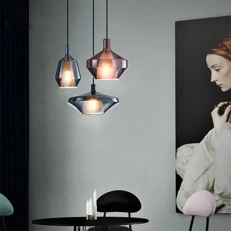 Three modern pendant lights with faceted copper and dark gray glass shades enhance home art decor above dining table