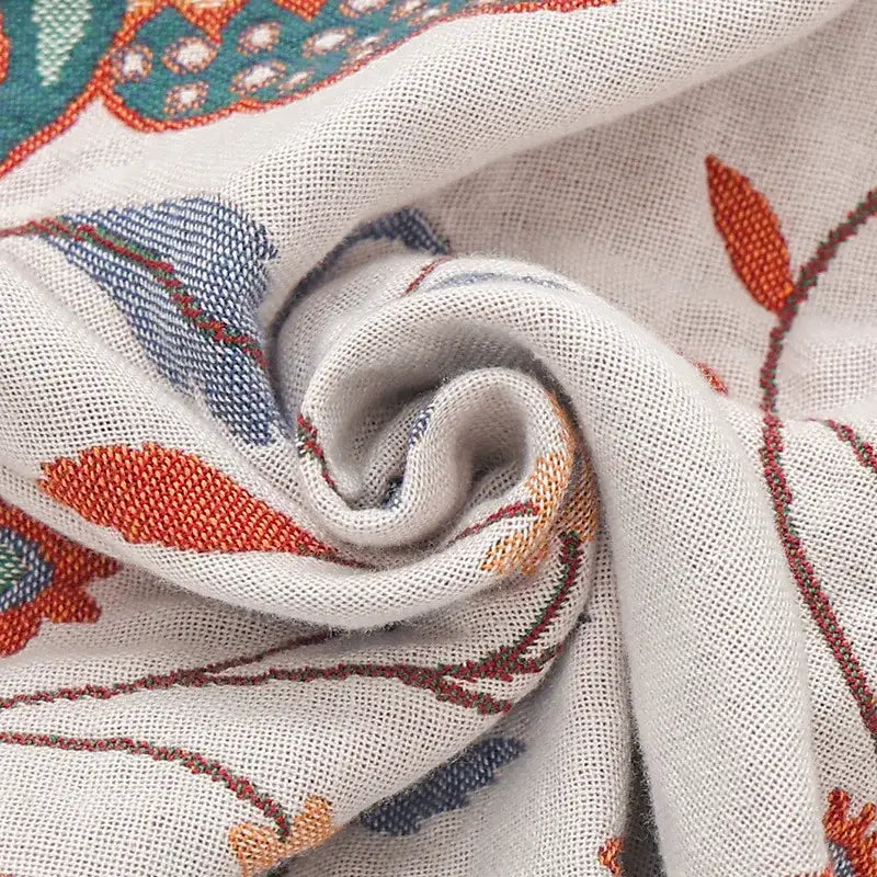 A soft off-white decorbites cooling cotton blanket with orange blue and teal floral embroidery for bedroom decor