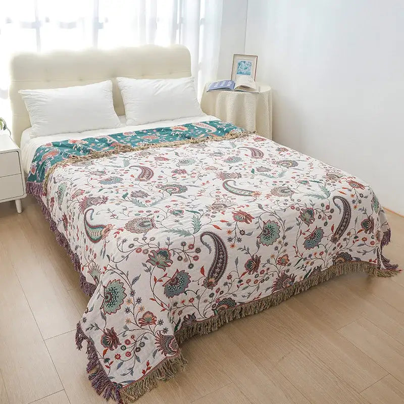 A cream and teal decorbites cooling cotton blanket with paisley patterns and fringe edges for bedroom decor
