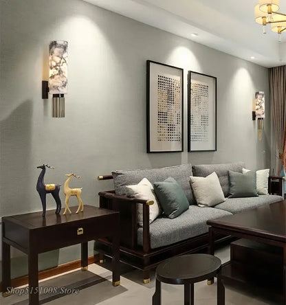 Dark wood side table with gold handle topped by blue and yellow deer figurines near decorbites dolomite marble wall light