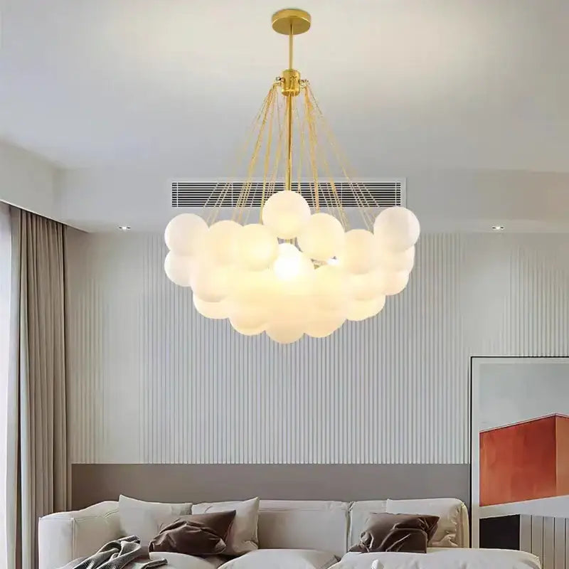 Gold-toned pendant lights with cluster of frosted glass ball spheres suspended by thin cords for dining room use