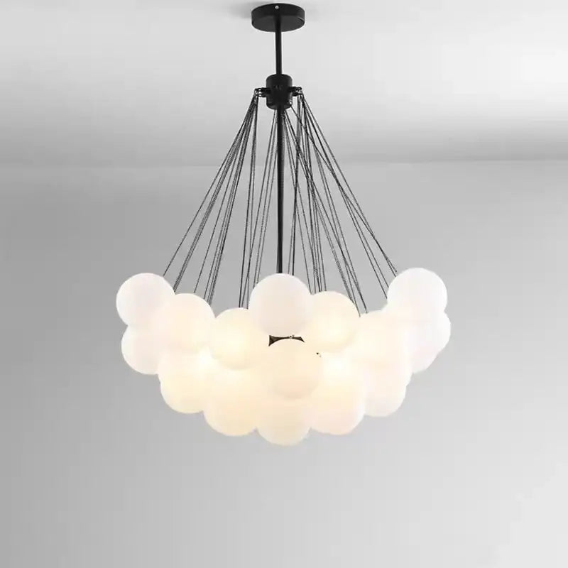 Modern pendant lights with frosted glass ball orbs suspended by black cords for dining room illumination