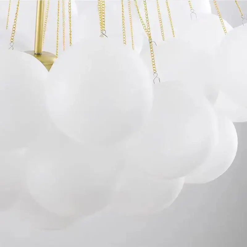 Modern white cloud-shaped pendant lights with frosted glass ball, gold-toned chains, and brass fixture for dining room