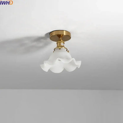 A delicate white frosted glass led ceiling light with ruffled flower design and polished brass mounting fixture