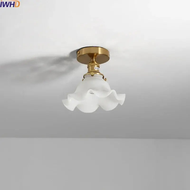 A delicate white frosted glass led ceiling light with ruffled flower design and polished brass mounting fixture