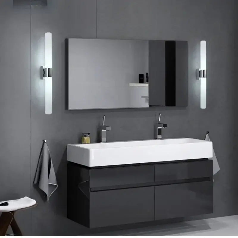 Modern frosted glass led wall lamp in gold silver and black above a black glossy vanity with white sink and chrome faucets