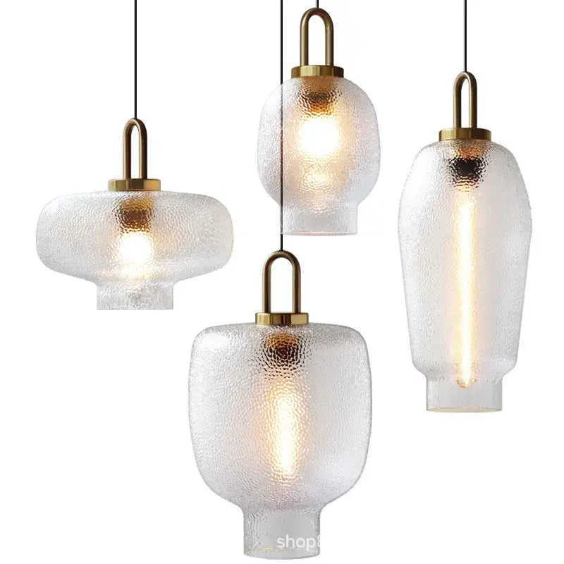 Set of four modern frosted glass pendant lights with textured glass and brass accents for kitchen lighting