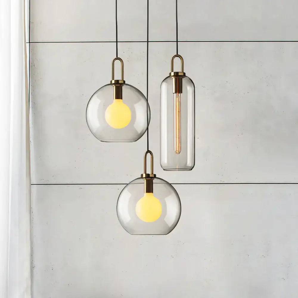 Modern frosted gray glass ball pendant light with brass accents and warm yellow bulbs for dining room decorbites glass ball