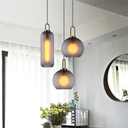 Three modern frosted gray glass ball pendant lights with brass accents hang from black cords in a dining room decorbites glass ball pendant set