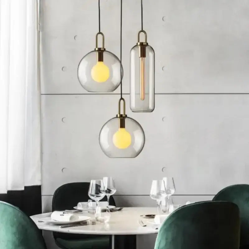 Modern frosted gray glass ball pendant light with brass accents and warm yellow bulbs perfect for kitchen lighting decorbites glass ball pendant