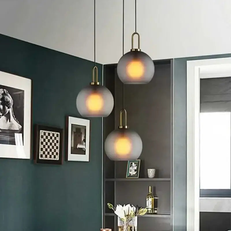 Modern frosted gray glass ball pendant light with brass accents featuring three hanging decorbites glass ball pendants