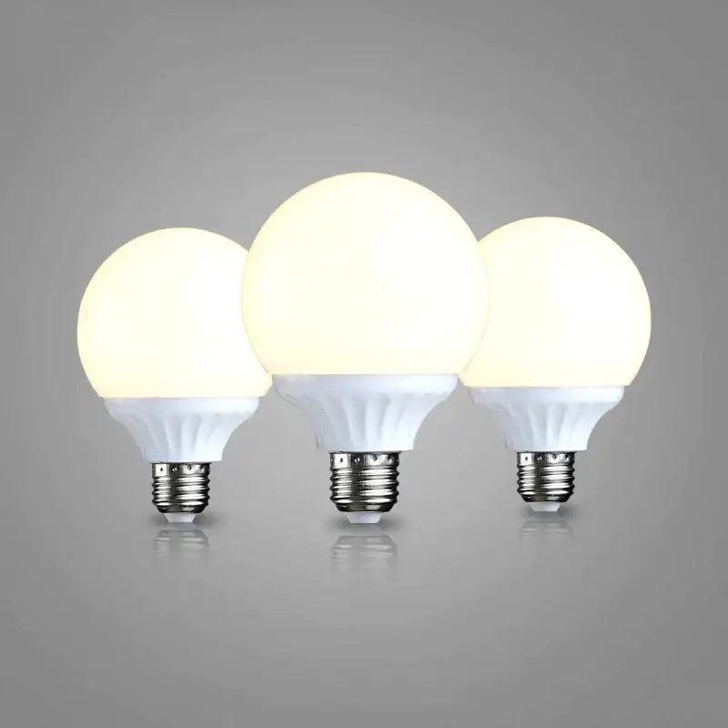 Three illuminated frosted white e27 9w led bulbs with metallic bases high brightness round lamps for bedroom use