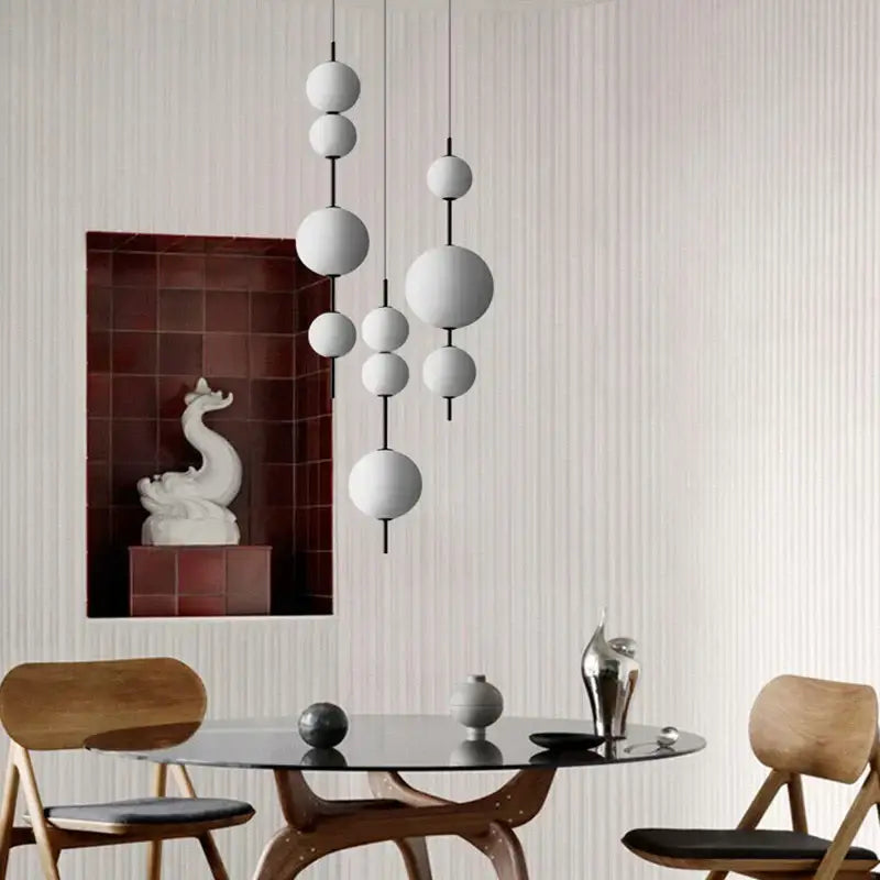Modern frosted white glass ball pendant lamp with black rods hanging from ceiling for dining room lighting