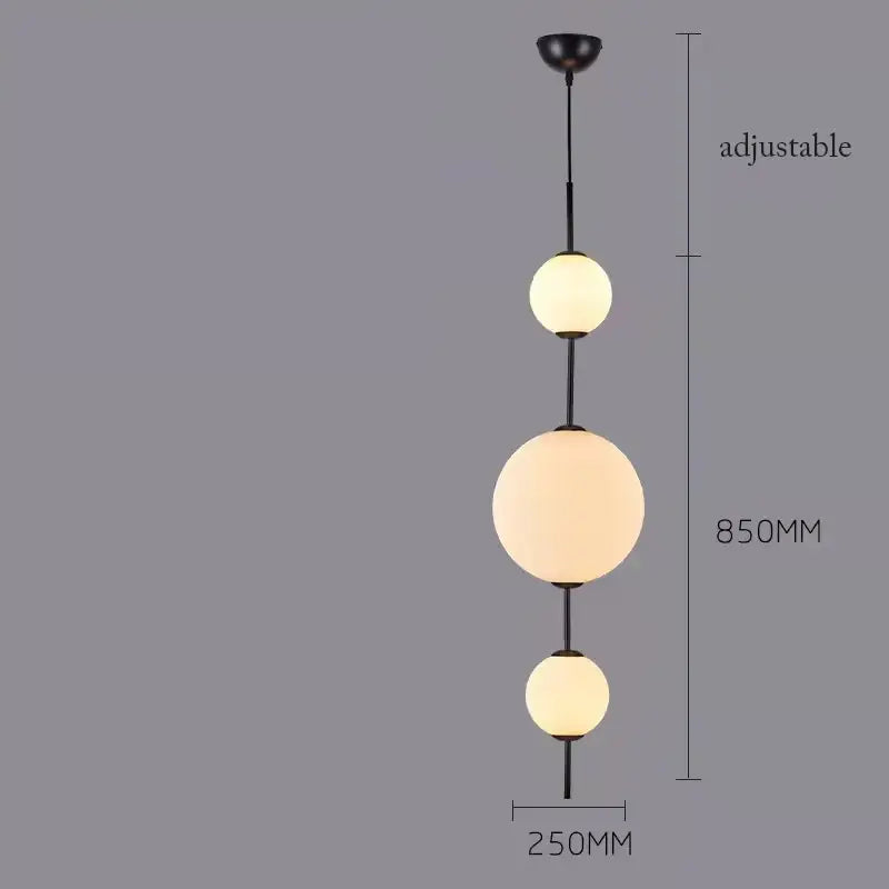 Black metal pendant lamp with three illuminated frosted white glass balls emitting a warm glow for dining room