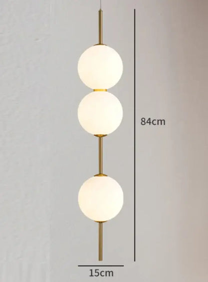 Gold-toned modern pendant lamp with three vertically stacked frosted white glass balls for dining room lighting