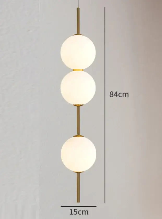 Gold-toned modern pendant lamp with three vertically stacked frosted white glass balls for dining room lighting