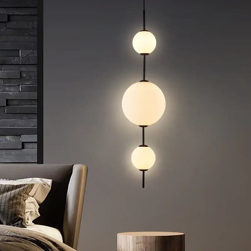 Modern pendant lamp with three glowing frosted white glass ball spheres suspended by black rods for dining room use