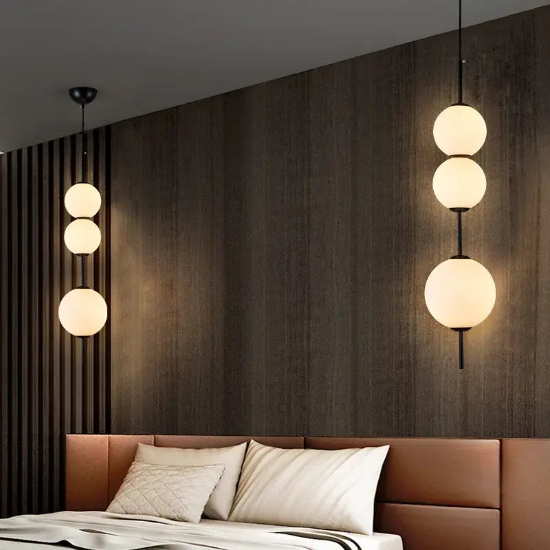 Modern pendant lamp featuring three stacked frosted white glass ball spheres suspended by black metal rods for dining room