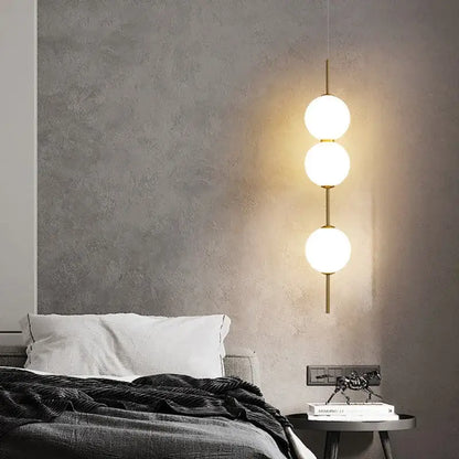 Modern three-bulb pendant lamp with frosted white glass ball shades and brass-toned rods for dining room lighting