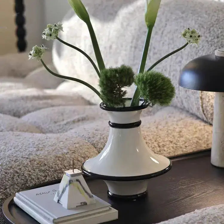 White ceramic vase with geometric black rim and white stripes holding green calla lilies for decorbites geometric black decor