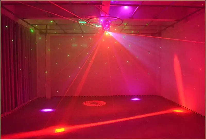 A modern geometric black light bar strobe projecting vibrant red and purple laser beams in a dimly lit room