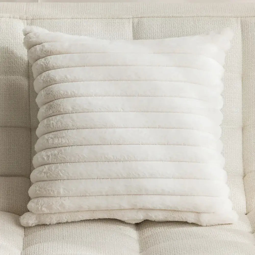 Cream-colored faux fur throw pillow with horizontal stitched ridges complementing embroidered pillow cover decor