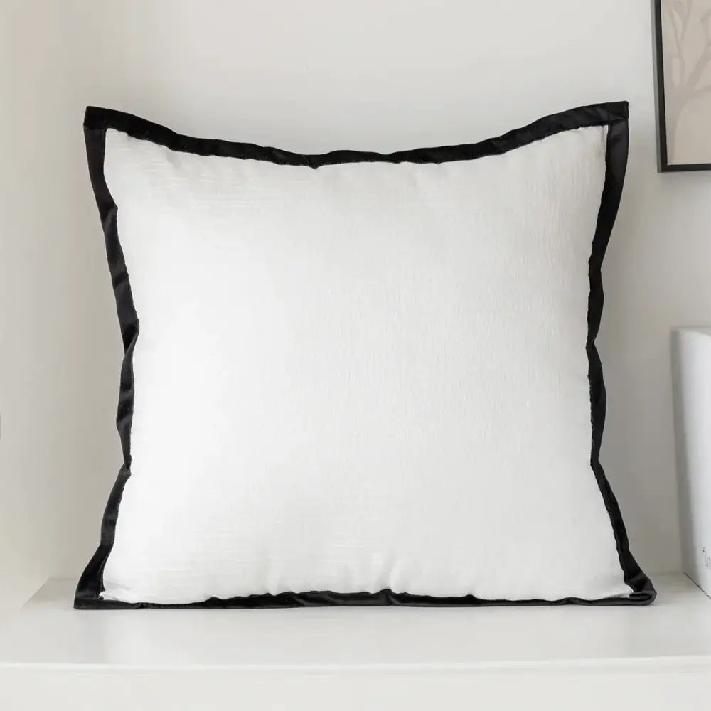 White square embroidered pillow cover with sleek black satin border for modern living room decor