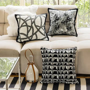 Three black and white geometric embroidered pillow covers on a beige sofa for modern living room decor