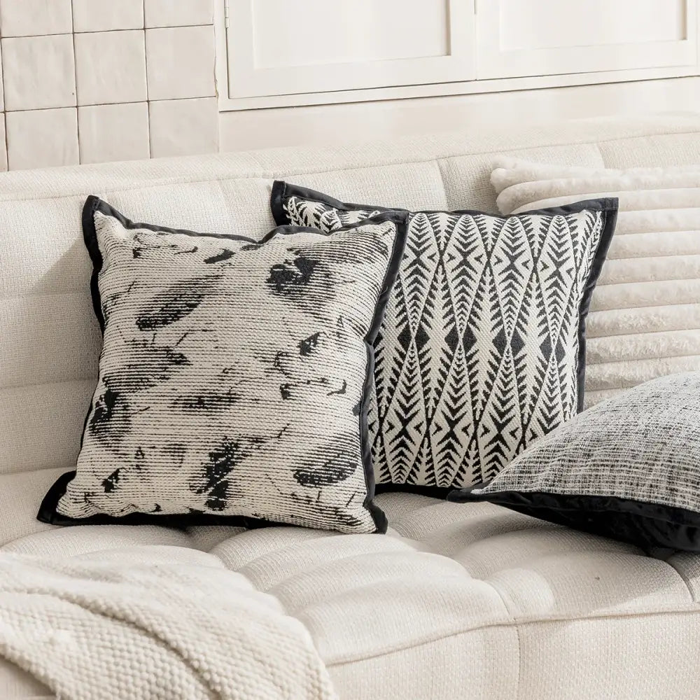 Modern geometric black and white embroidered pillow cover with textured fabric and contrasting black trim for living room