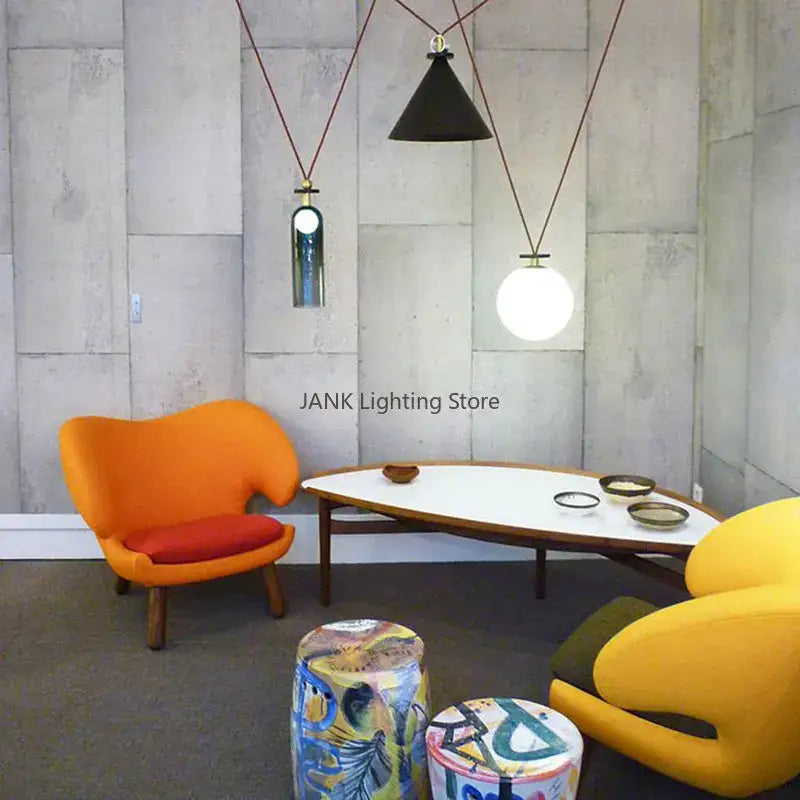 Vibrant orange upholstered armchair with red cushion and wooden legs under modern geometric brass and black glass pendant light
